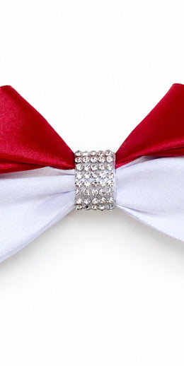 A close-up of a bow tie with red satin wings, a white satin wing, and a rhinestone-encrusted silver center band, shown on a plain white background.