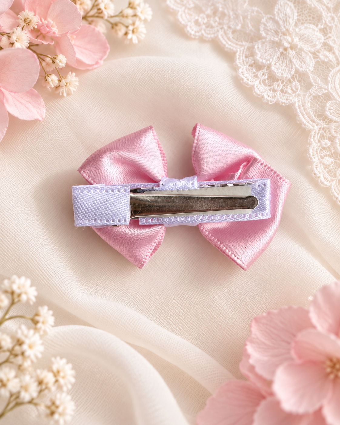 Little Petal, petite 2-inch blush pink satin hair bow held in hand to show size