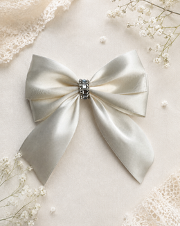 The Signature Rhinestone Satin Bow, approximately 5.5-inch satin hair bow held in hand to show size