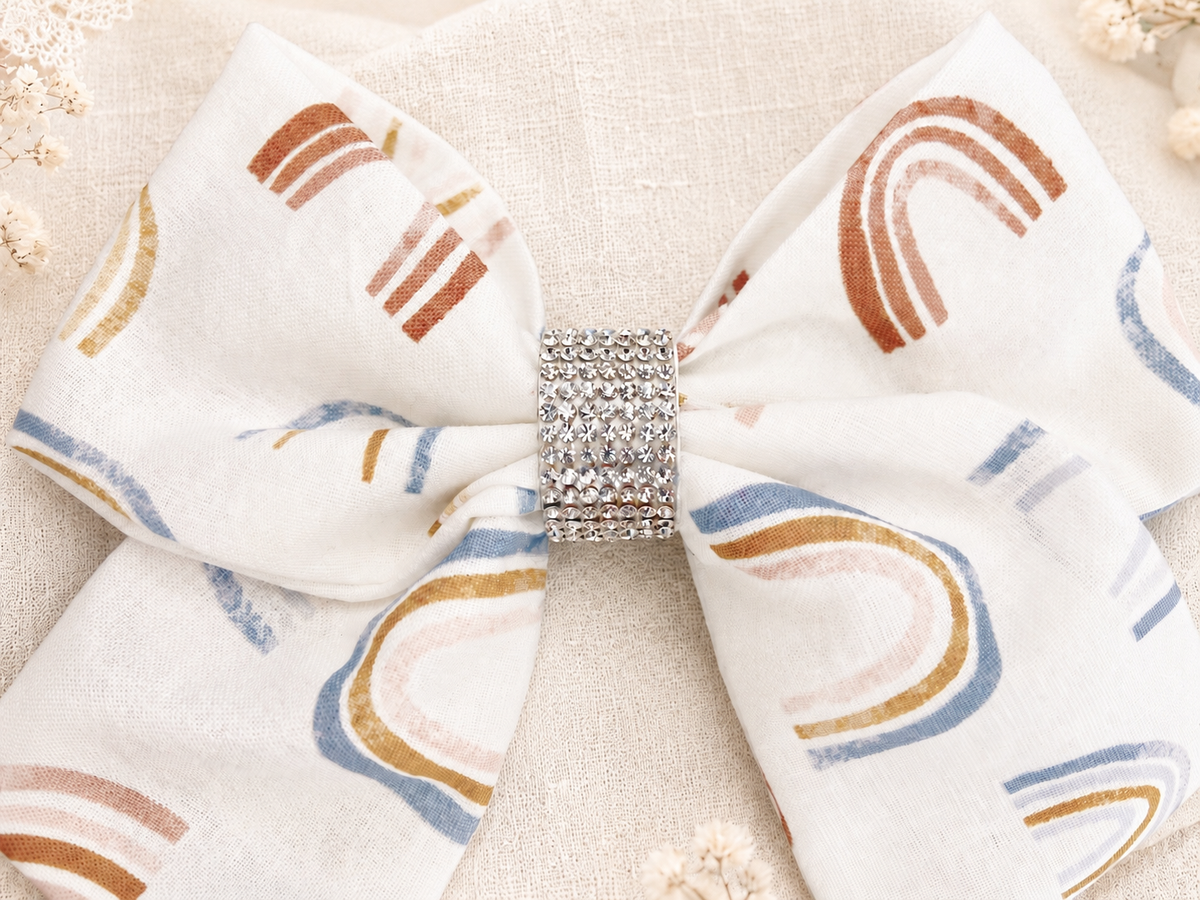 Angled product view of Golden Skies Bow, approximately 6-inch ivory rainbow hair bow