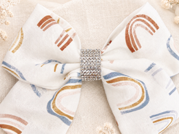 Angled product view of Golden Skies Bow, approximately 6-inch ivory rainbow hair bow