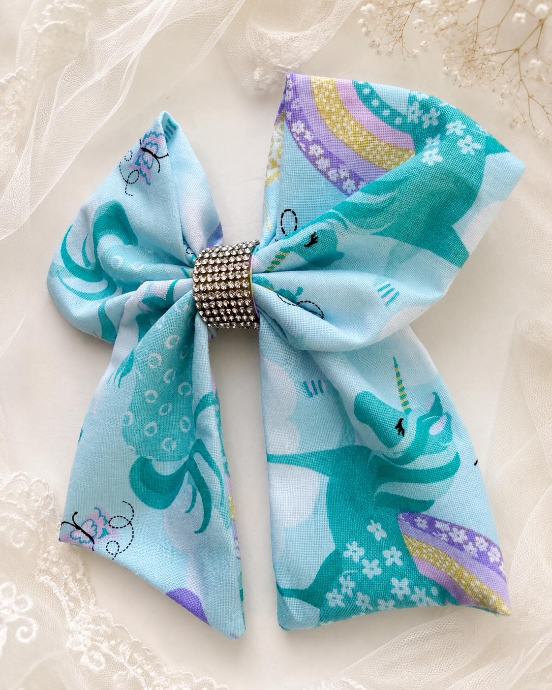 Unicorn and rainbow print boutique hair bow on light blue fabric