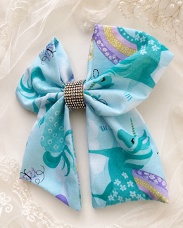 Unicorn and rainbow print boutique hair bow on light blue fabric