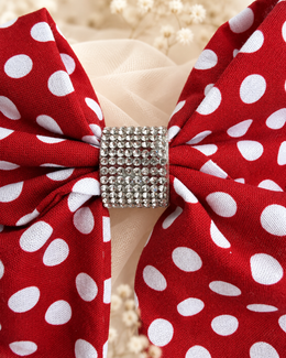 Close up of red and white polka dot fabric hair bow with rhinestone center