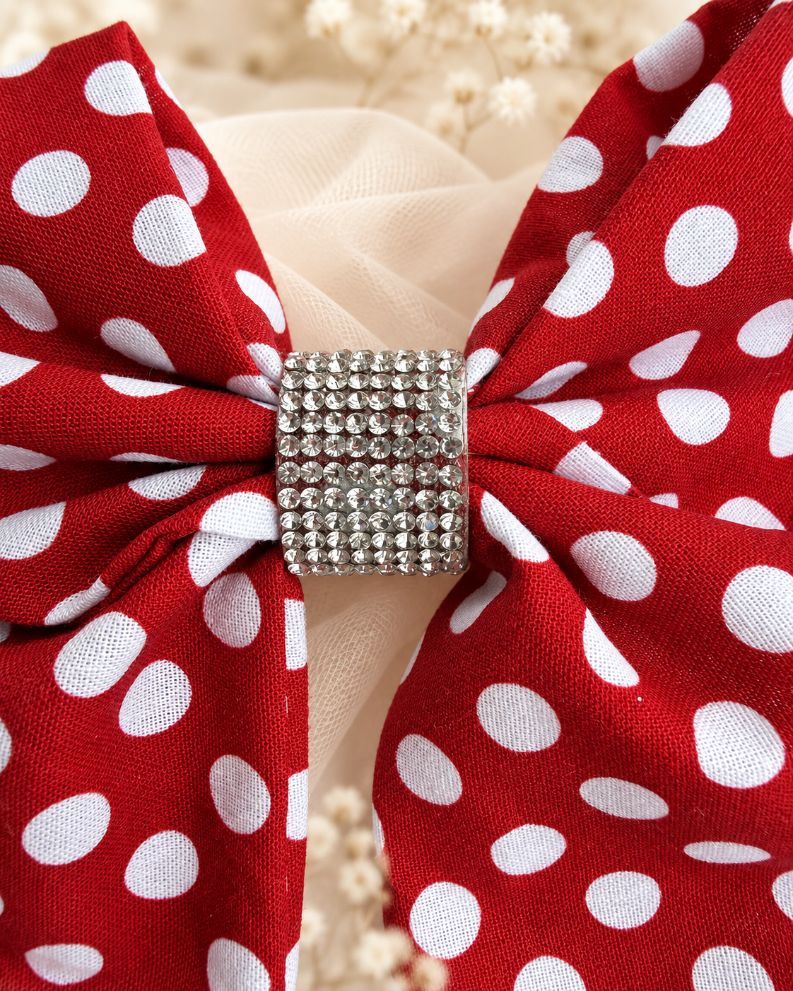 Close up of red and white polka dot fabric hair bow with rhinestone center