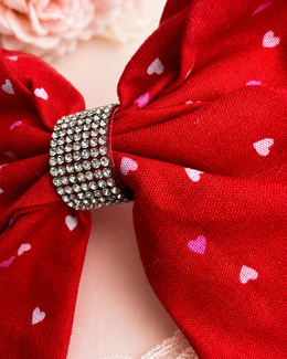 Love Letter Bow, approximately 6-inch red heart-print hair bow held in hand to show size