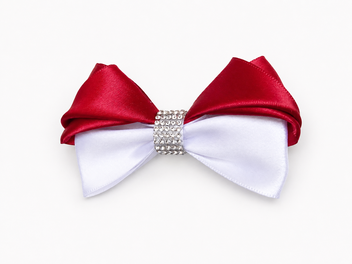 A satin bow accessory with a top half in deep red and a bottom half in white, centered with a sparkling rhinestone band.