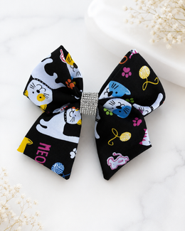 Black cat print 6 inch hair bow with colorful paw prints and rhinestone center