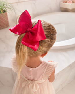 The Classic Everly Bow, approximately 5.5-inch satin hair bow worn in a girl's hairstyle to show scale