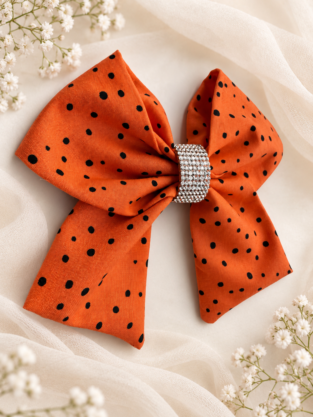 Close up of rhinestone center on orange polka dot fabric hair bow