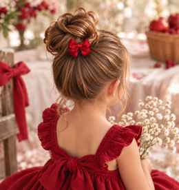 Little Ruby red satin mini bow styled in a girl's hairstyle