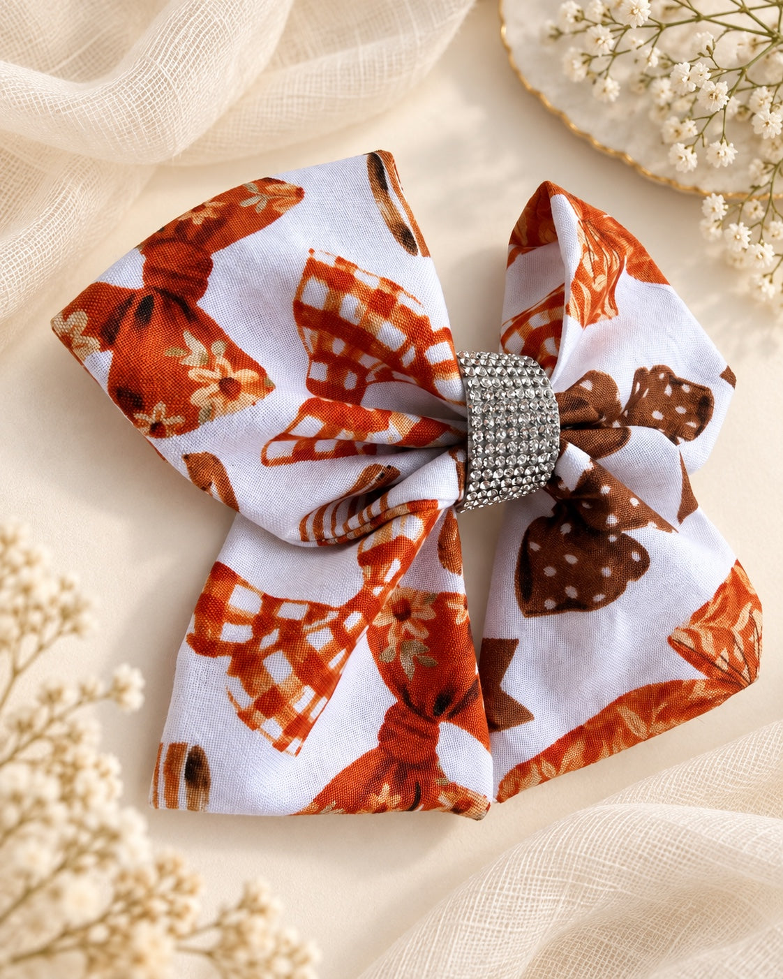 Angled front view of Autumn Ribbons 5.5 inch rust orange and brown fall hair bow with rhinestone center