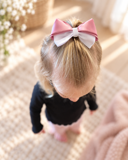 Little girl wearing a Blushing Pearl 3.5 inch pink and white satin hair bow in a ponytail
