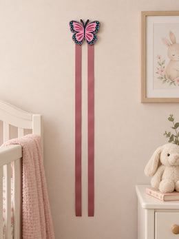 Two-ribbon butterfly bow holder in a soft nursery setting