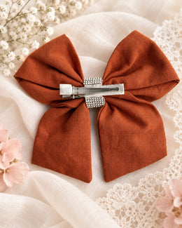 Back of burnt orange rhinestone hair bow with alligator clip