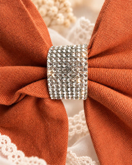 Close up of burnt orange fabric hair bow with sparkling rhinestone center