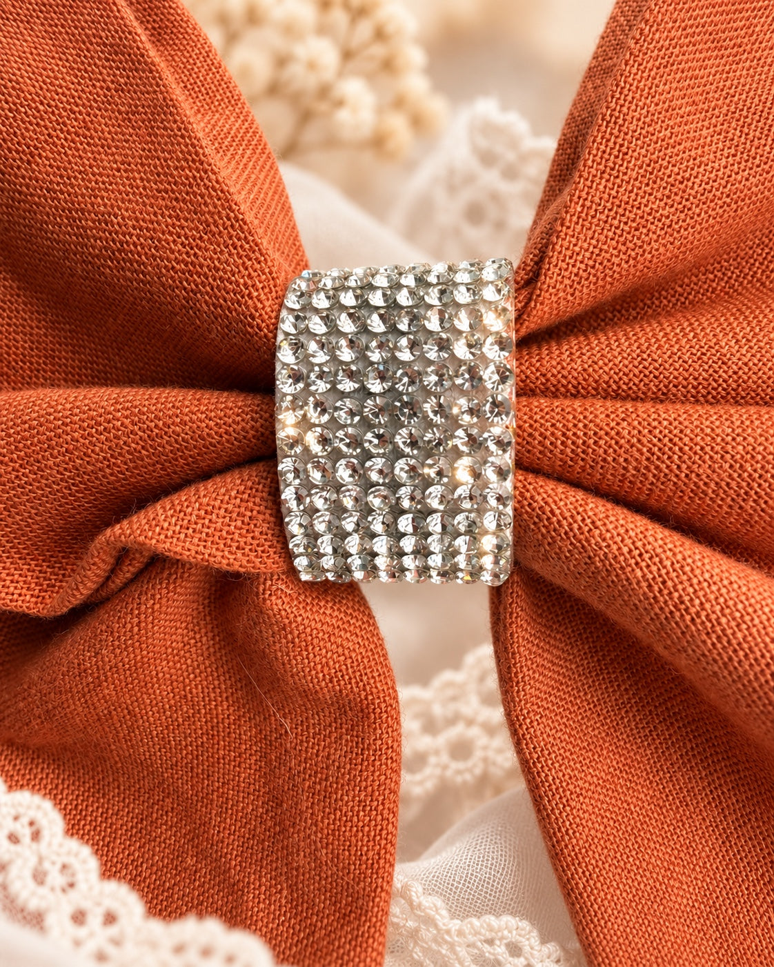Close up of burnt orange fabric hair bow with sparkling rhinestone center
