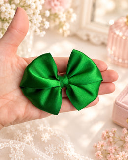 4 inch emerald green satin girls hair bow shown in hand