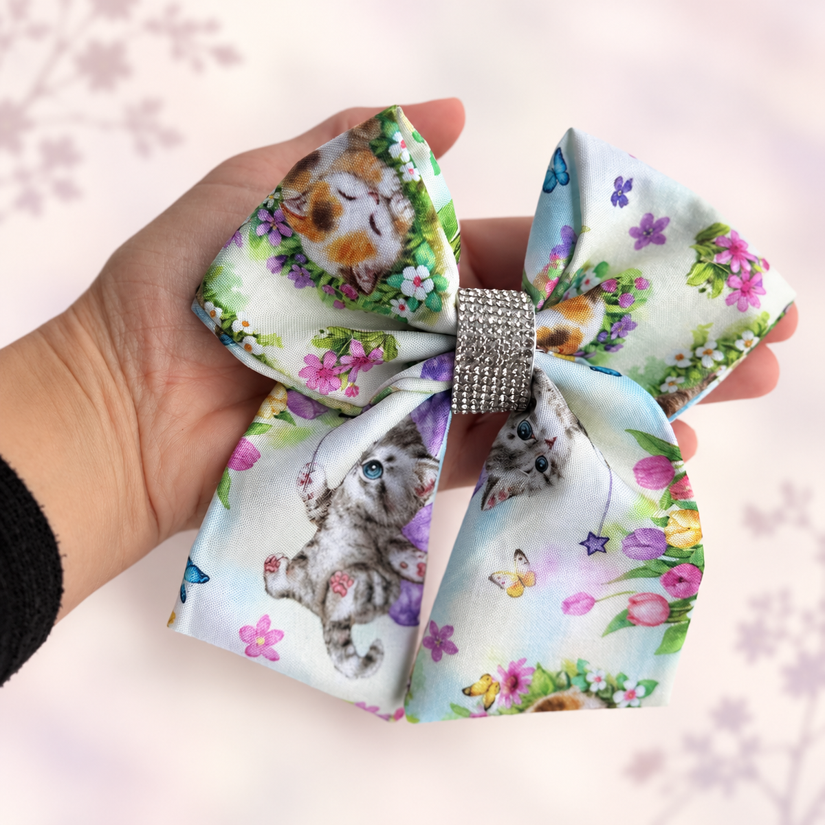 Six-inch kitten hair bow held in hand to show its size and shape