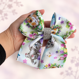 Six-inch kitten hair bow held in hand to show its size and shape