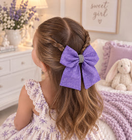 Girl wearing lavender purple rhinestone hair bow in half-up braided hairstyle