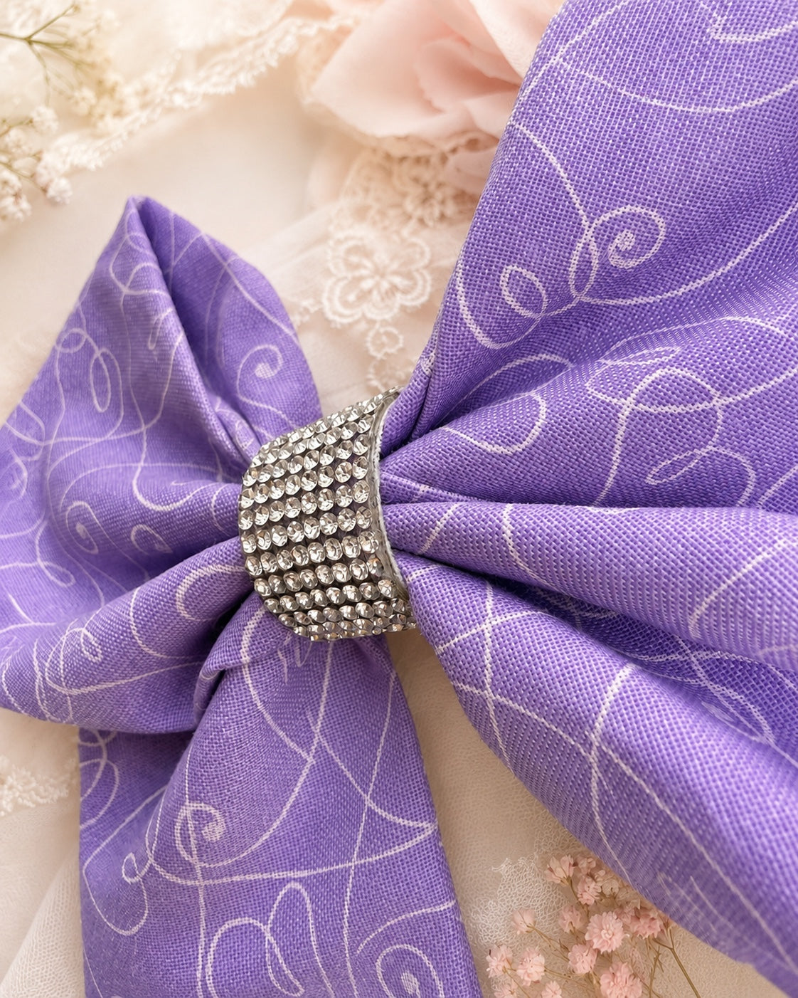 Close-up of lavender purple hair bow with sparkling rhinestone center and swirl print