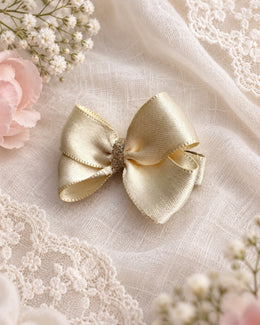 angled view of 2 inch champagne satin hair bow with glitter center
