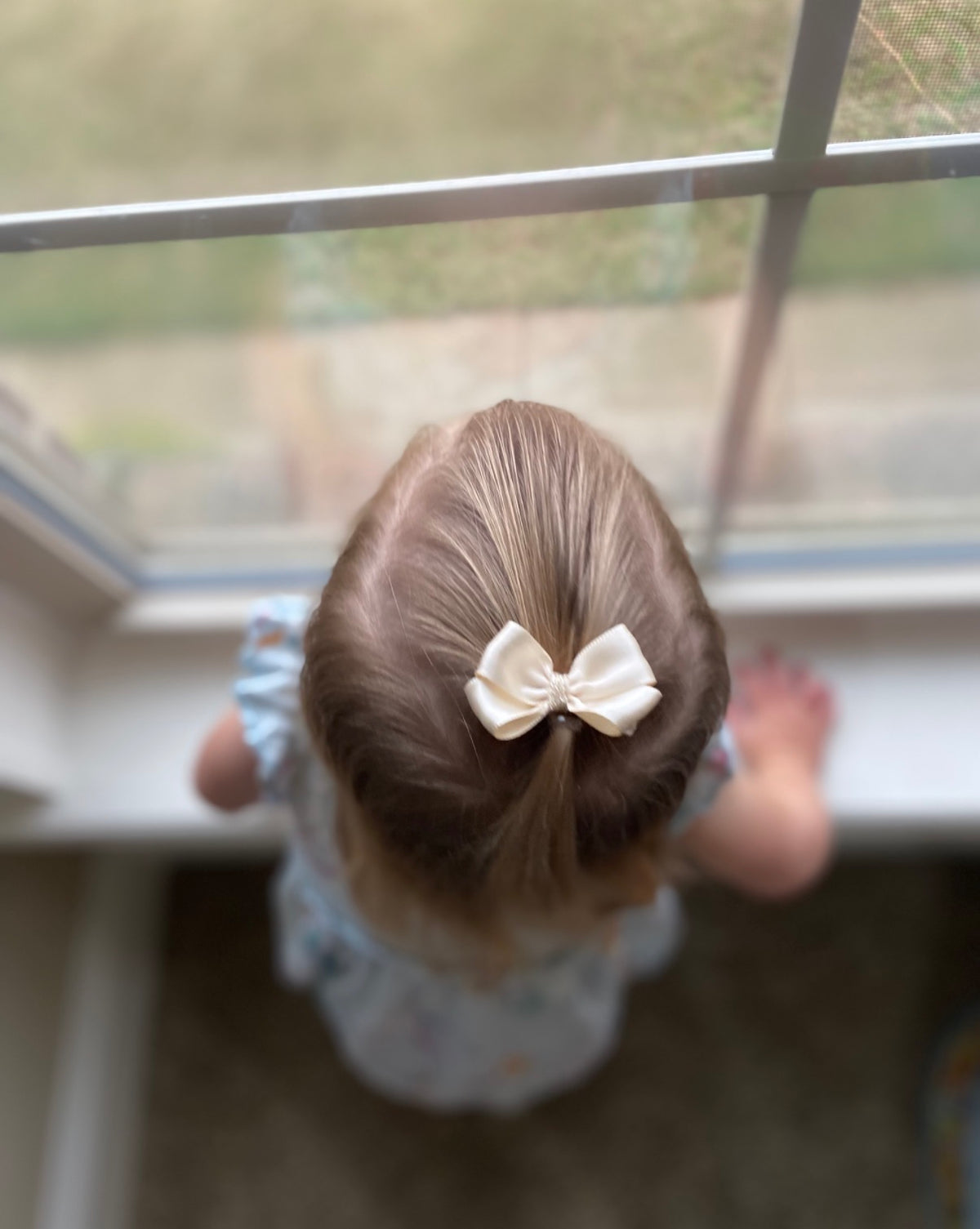 2 inch champagne satin mini hair bow worn in a little girl's ponytail