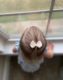 2 inch champagne satin mini hair bow worn in a little girl's ponytail