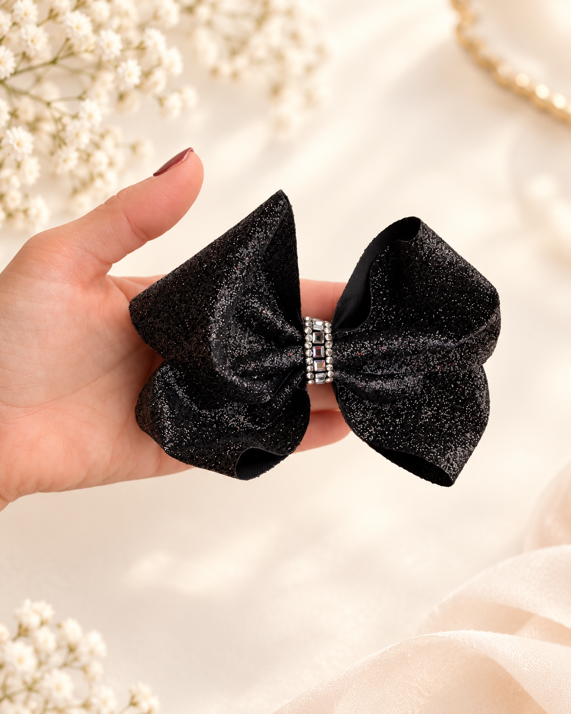 5.5 inch black glitter hair bow shown in hand for size reference