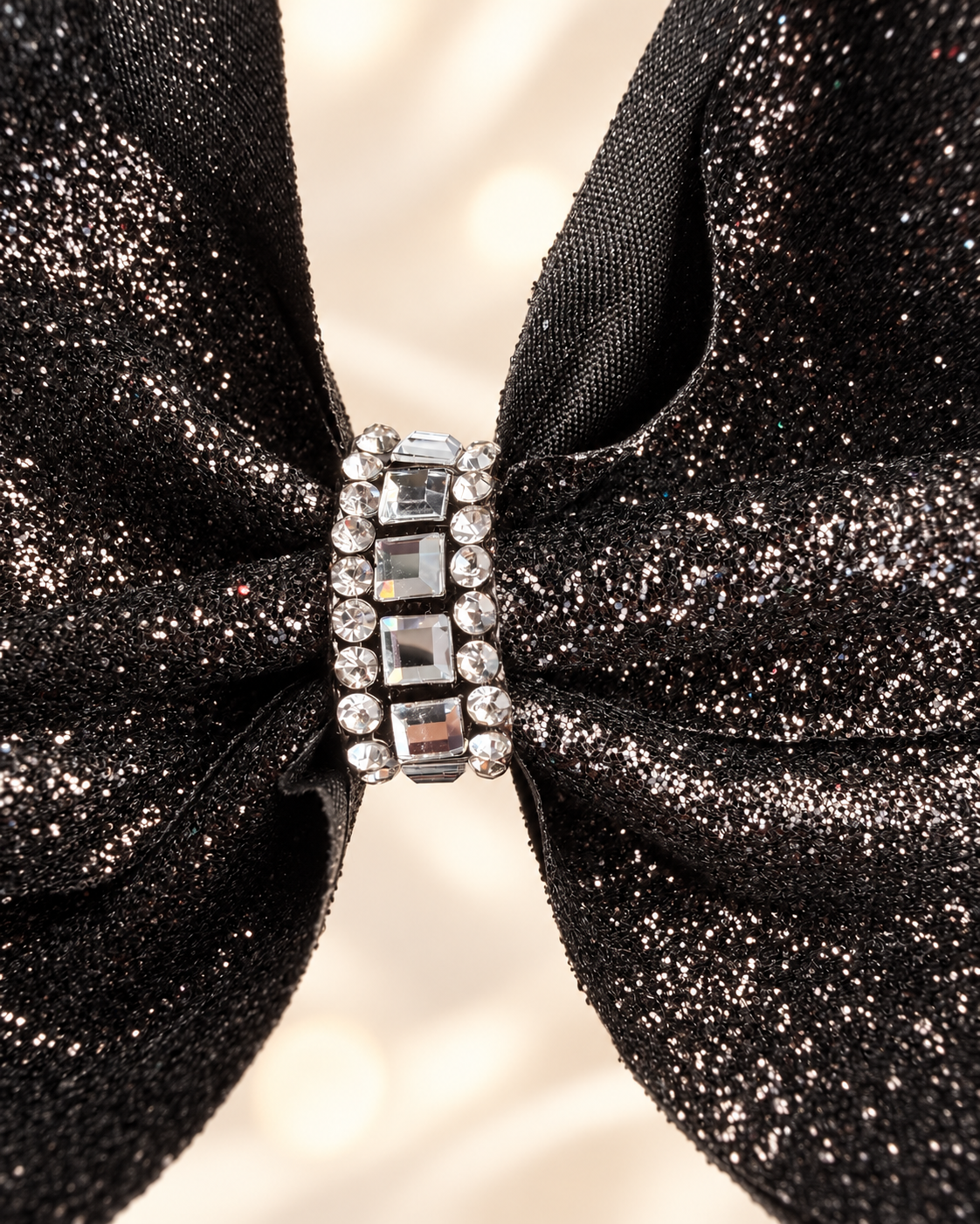 Close up of rhinestone crystal center and black glitter fabric on girls hair bow
