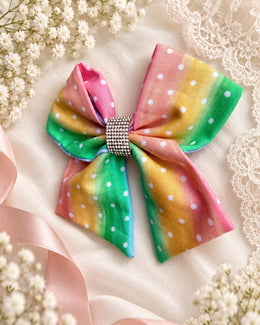 Pastel rainbow polka dot bow with rhinestone center angled view