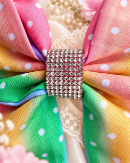 Close up of pastel rainbow polka dot hair bow with sparkling rhinestone center