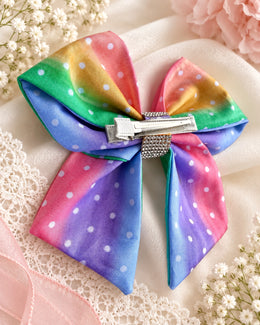 Sparkling rhinestone center detail on pastel rainbow polka dot hair bow